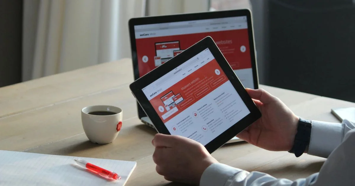 Digital professional working on website design and maintenance across tablet and laptop devices.