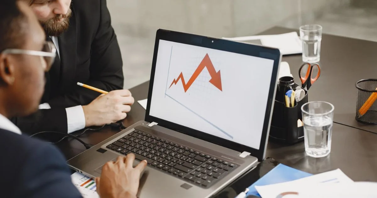 Colleagues in a meeting looking at a chart depicting declining business performance and market trends