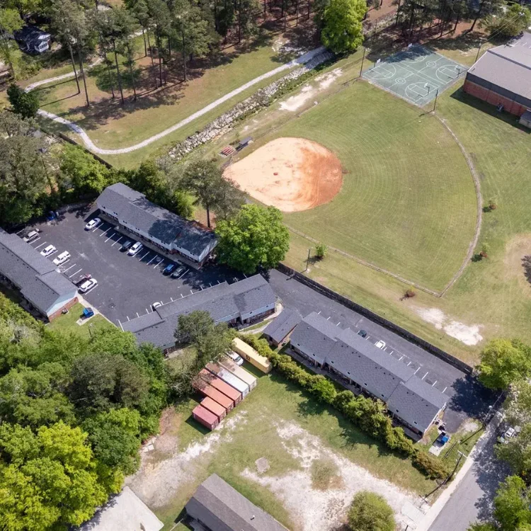 Overhead drone shot highlighting local community spaces, commercial buildings, and area properties.