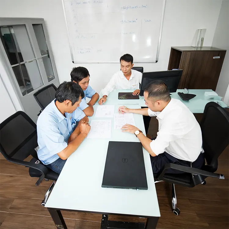 Engineering and project management team collaborating over architectural drawings and schematic documents during a meeting.
