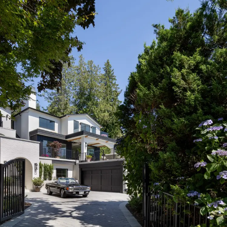 Luxury modern home exterior with gated entry, garage, upper balcony, and a vintage Mercedes convertible in the driveway.